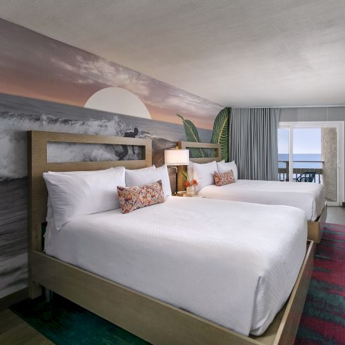 A tidy hotel room with a large bed, nightstands, a desk, and a window letting in light.