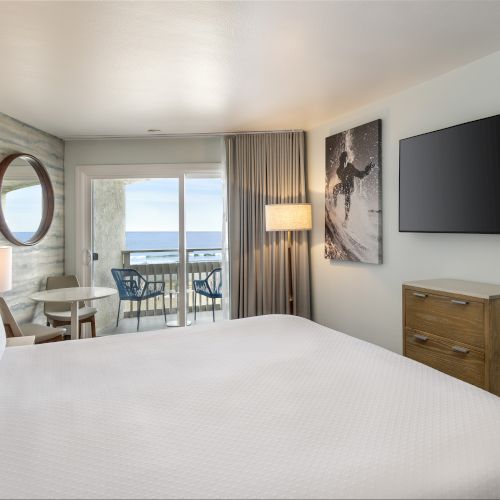 A bright, modern bedroom with a bed, side tables, wall-mounted TV, large window with curtains, and cozy decorations.